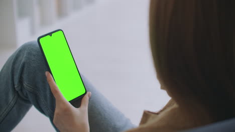 Young-Girl-Is-Holding-Smartphone-With-Green-Screen-At-Evening-Time.-Smartphone-in-hand-static-footage-with-little-hand-moves.-indicators-on-screen-to-track-movement